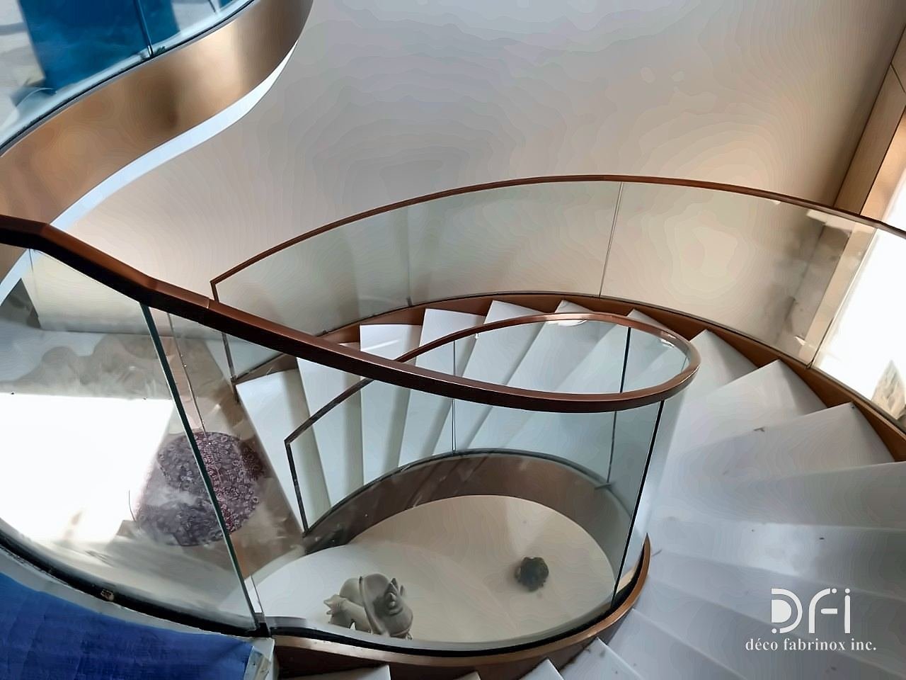 Spiral staircase with a curved glass and bronze balustrade, from above