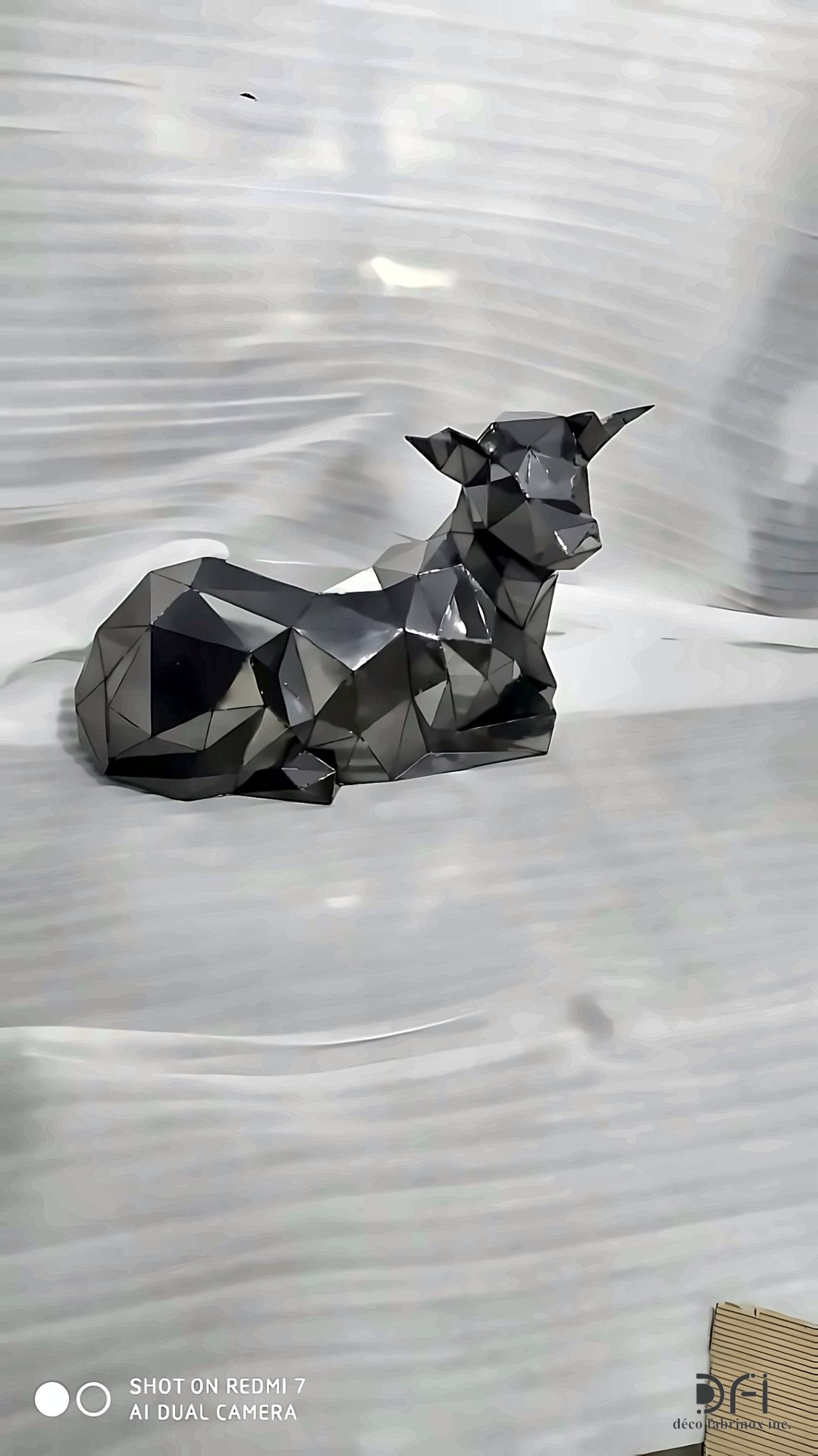 Faceted blackened metal sculpture of a resting calf