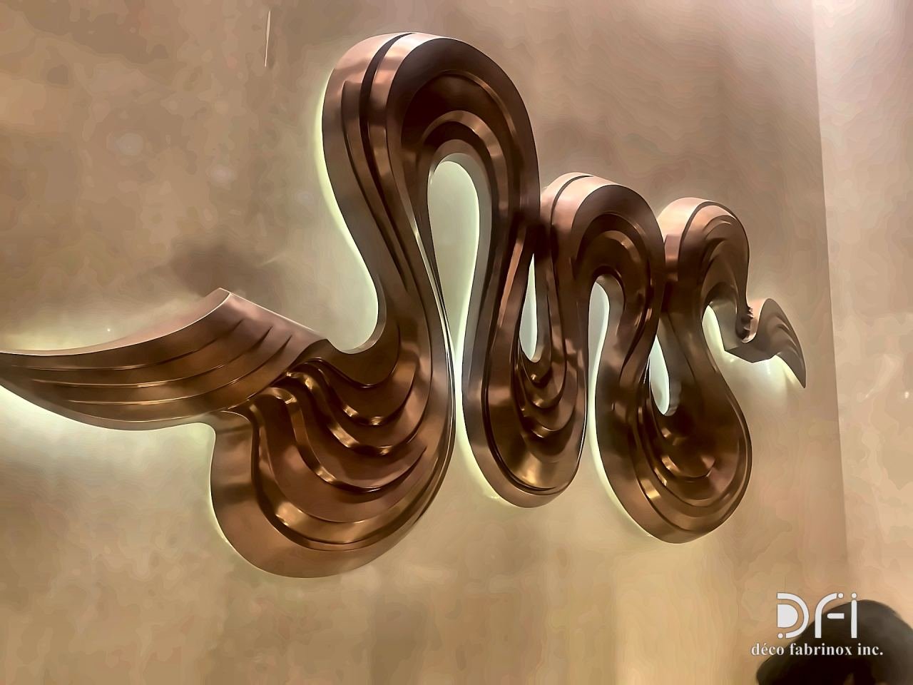 Copper ribbon sculpture in the form of a serpent on a wall