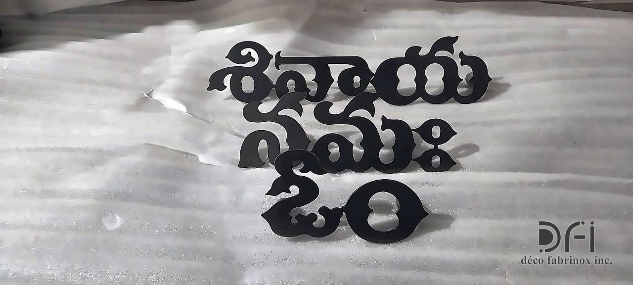 Black metal lettering in Telugu script on a stone surface