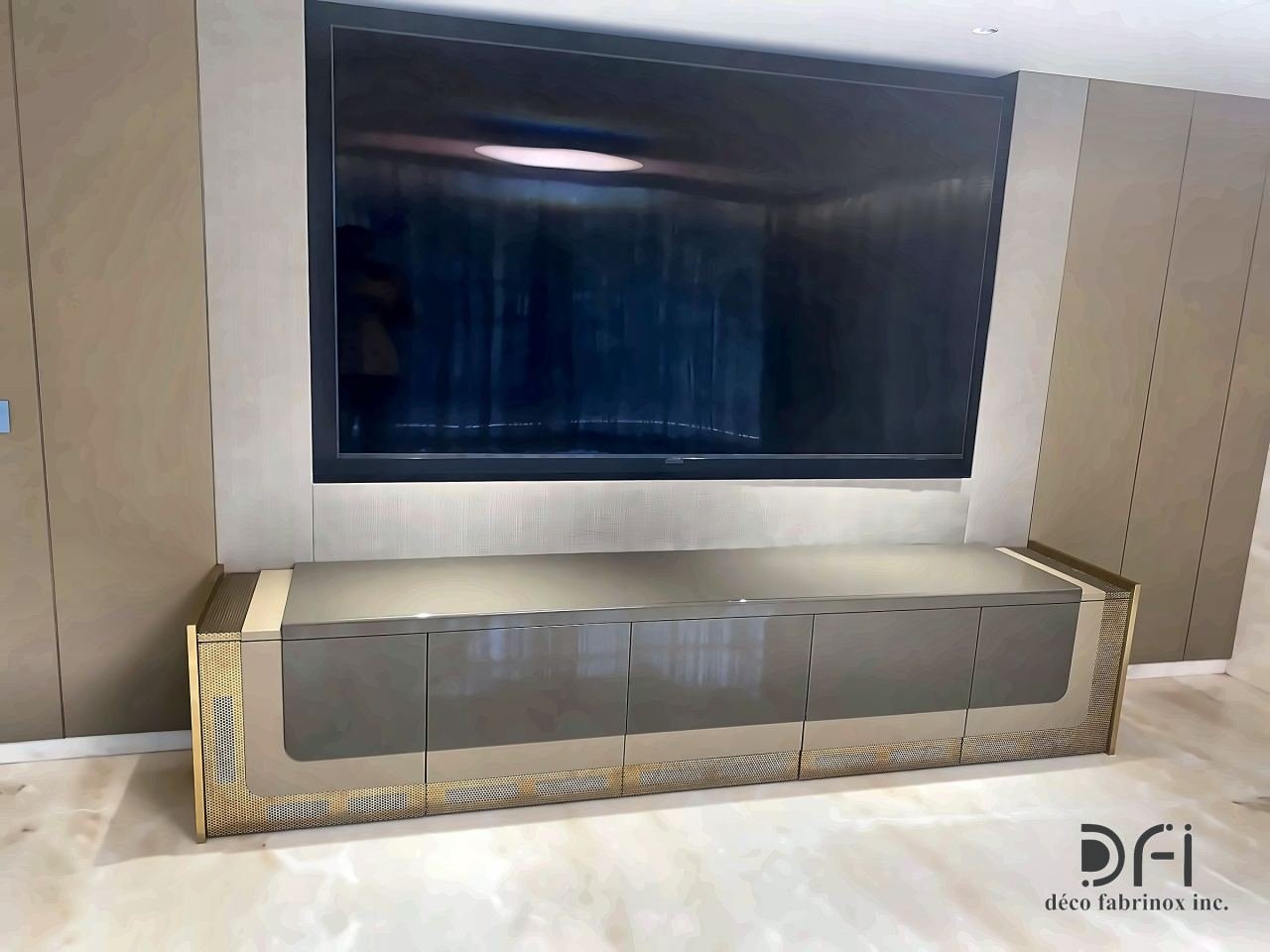 Low media console with brass detailing below a wall-mounted screen