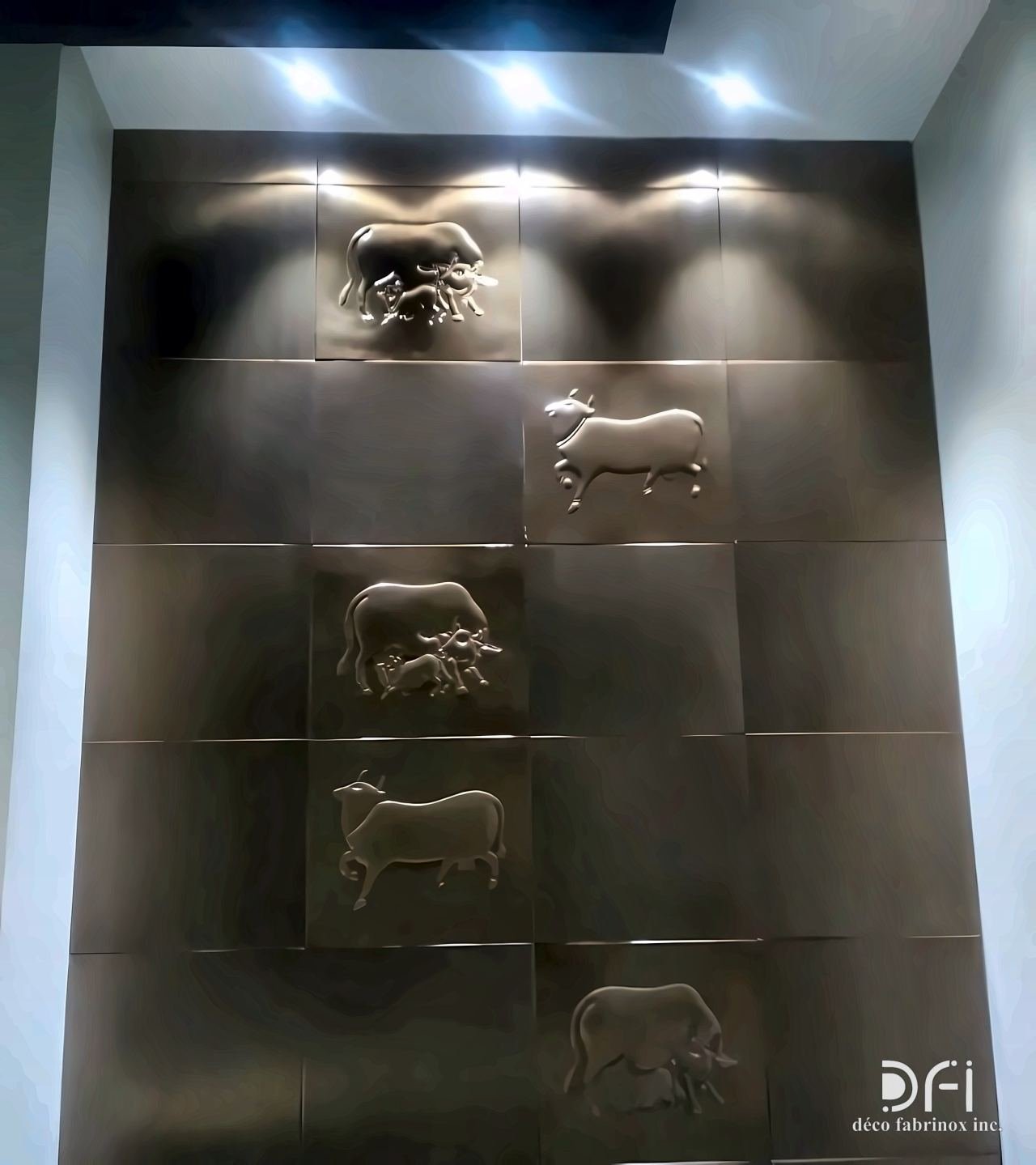 Bronze wall panels with relief animals, lit from above