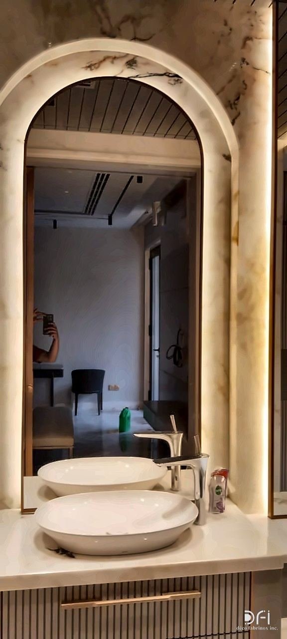 Arched mirror with a metal frame and concealed lighting above a vanity