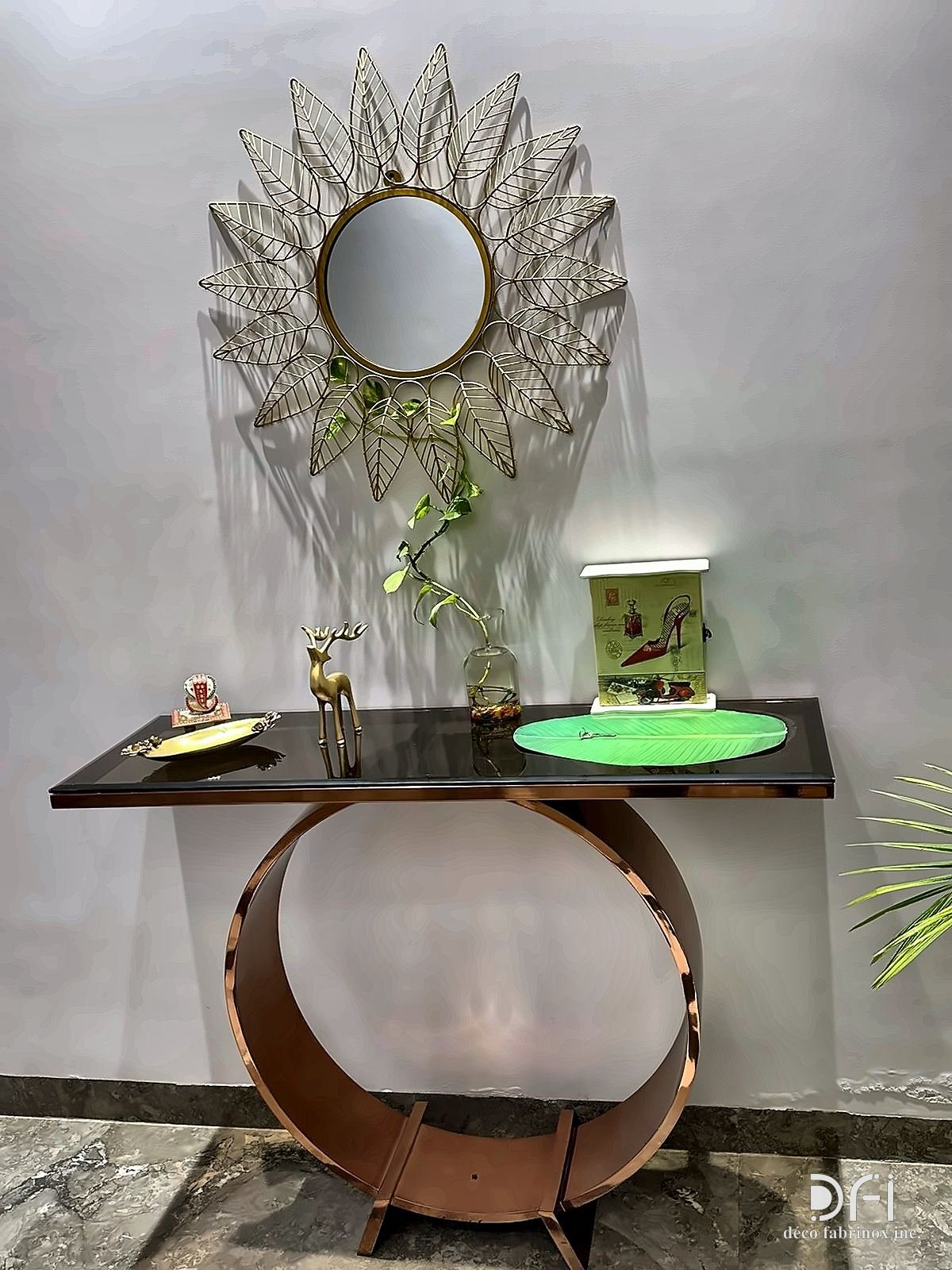 Sunburst metal mirror above a console with a curved metal base
