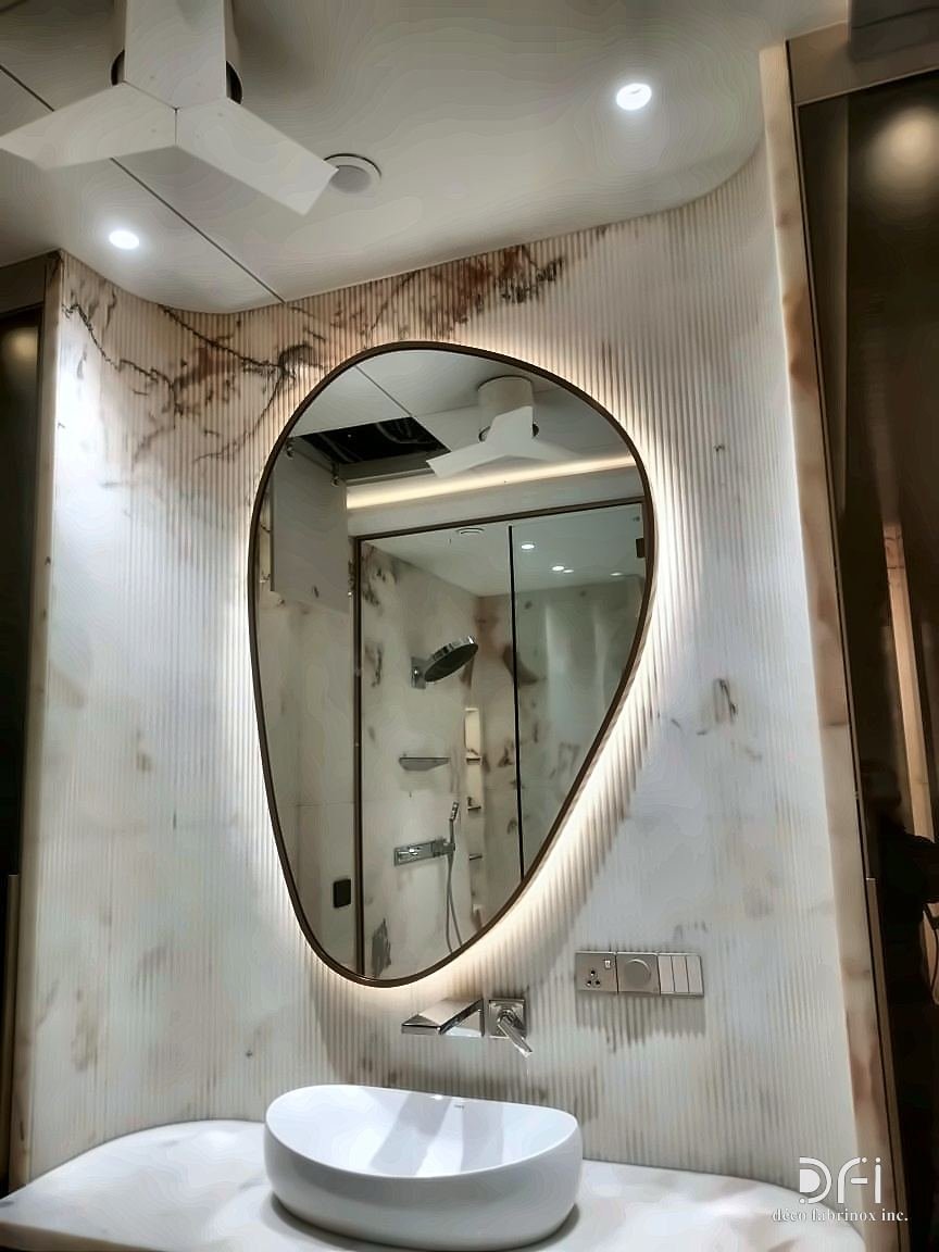 Pebble-shaped halo-lit mirror with a fine metal frame above a basin