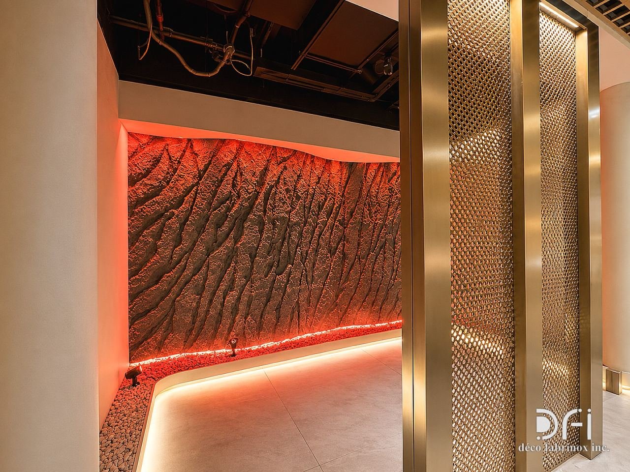 Perforated brass panels beside a lit textured feature wall