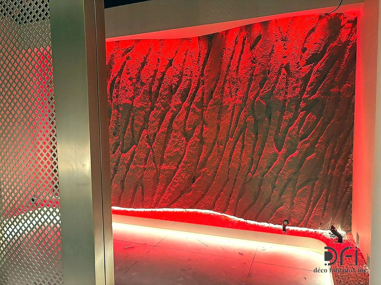 Red-lit textured feature wall framed in brass