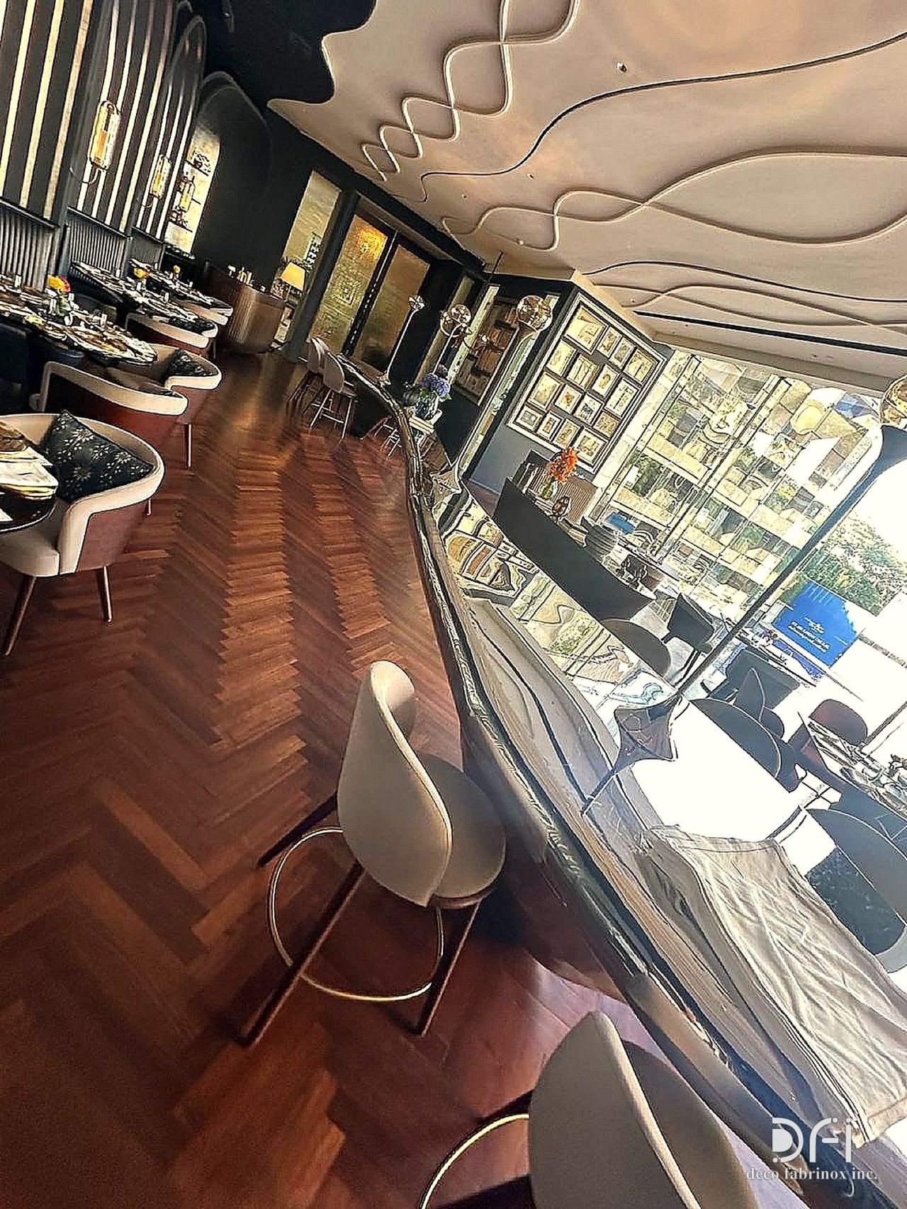 Restaurant bar counter in polished metal under a sculpted ceiling
