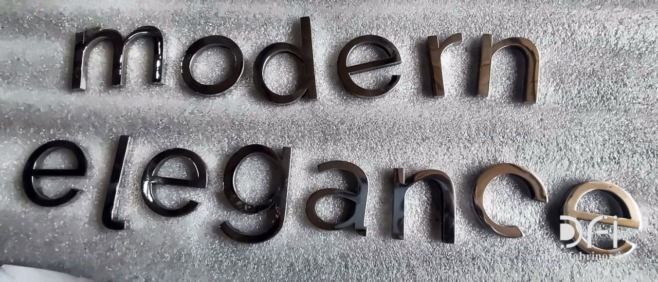 Brass cut letters spelling “modern elegance”, laid out before fixing