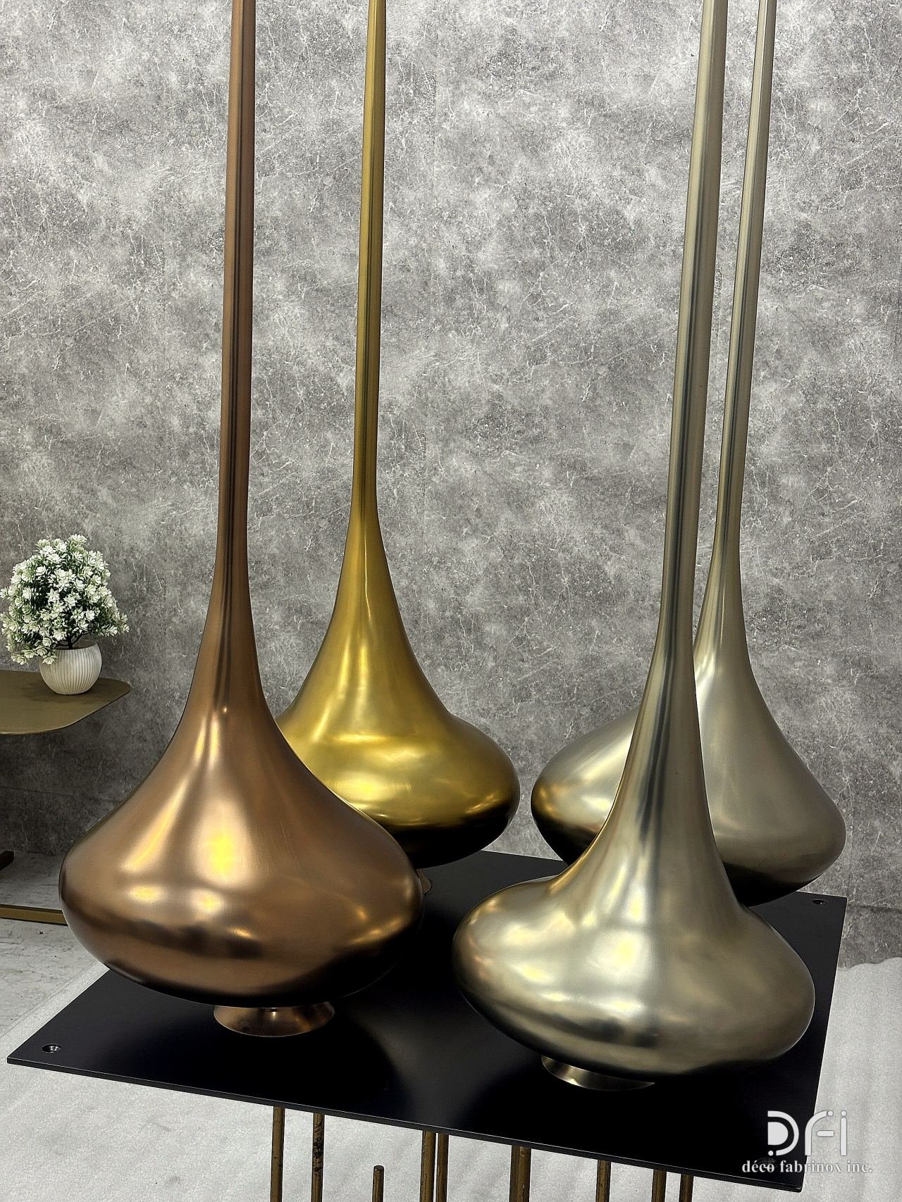 Teardrop sculptures in gold, champagne and copper finishes on a black base